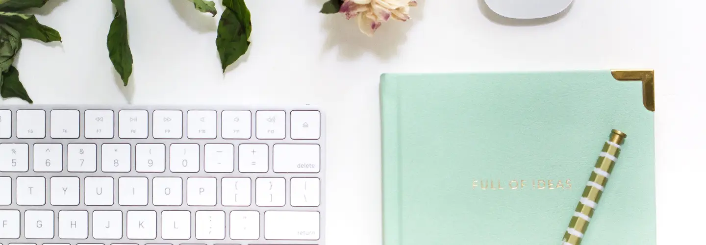 Un carnet, un stylo et un clavier posés sur un bureau clair