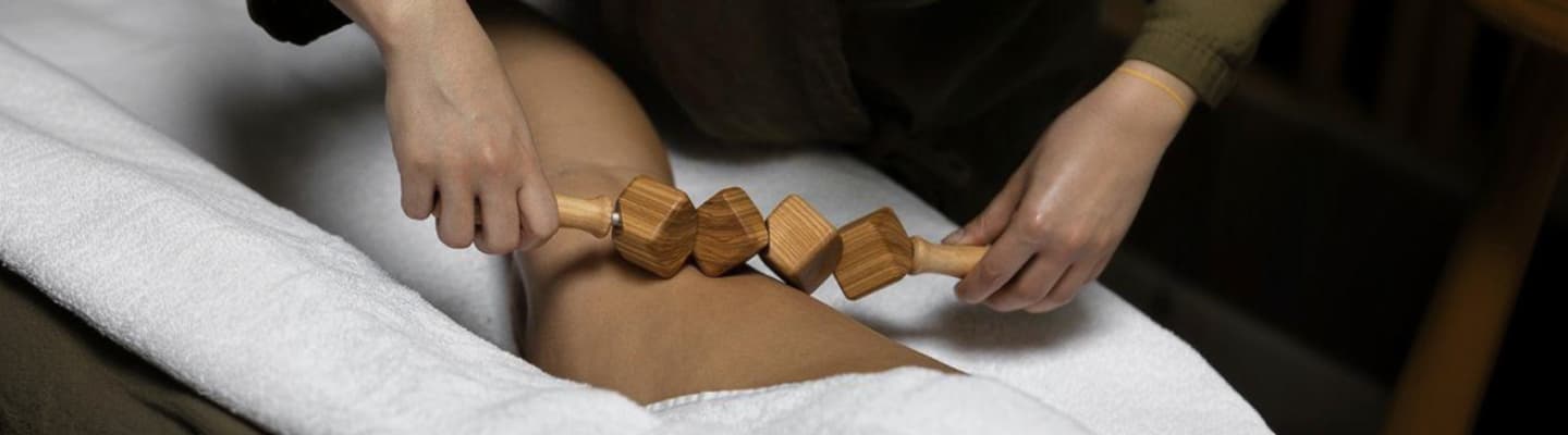 Massage d’une jambe avec un rouleau en bois